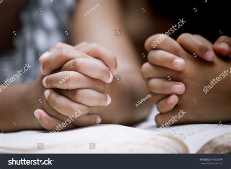 Two Little Girl Hands Folded In Prayer On A Holy Bible Together For