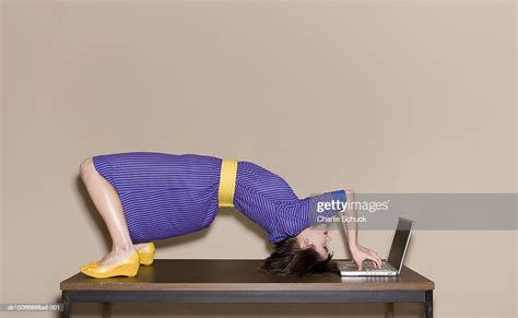 Woman Bending Over Backwards On Table While Working On Laptop Foto De