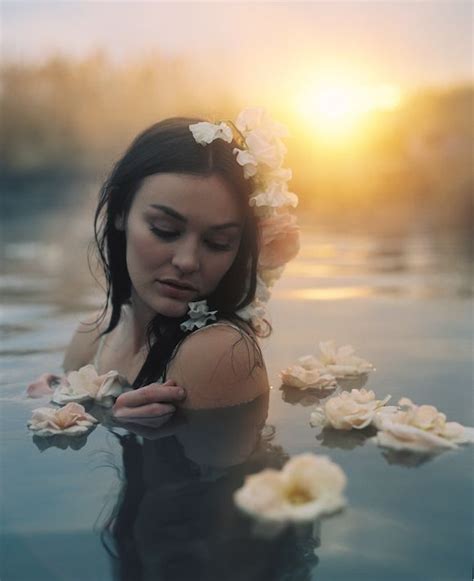 A Woman Is Floating In The Water With Flowers Around Her Neck And Hands