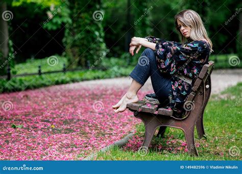 Barefoot Woman Is Sitting On A Bench At Alley With Blossom Trees Stock Photo Image Of Cute
