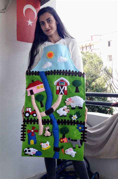A Woman Holding Up A Piece Of Art Made To Look Like A Farm Scene With