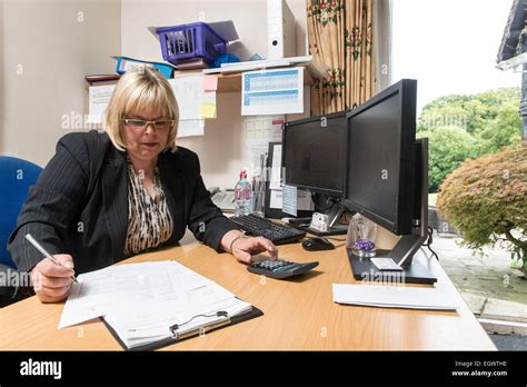 A Business Administrator Office Manager By Her Desk In A Busy Office Environment Managing