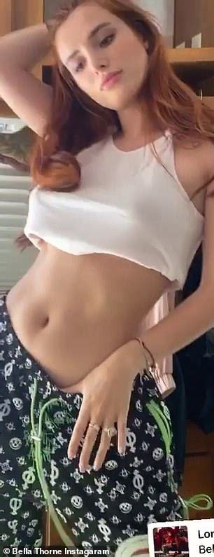 bella thorne flashes some underboob and her toned tum as she goes braless under white vest top