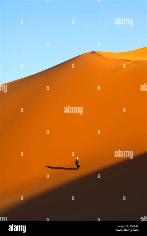Bedouin Man Climbing At Sunset A Pristine Sand Dune In The Sahara