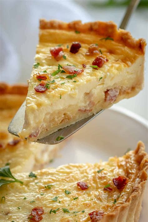 A Piece Of Quiche On A White Plate With A Silver Serving Spoon In It