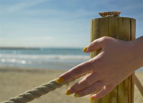 uma mão feminina toca uma corda esticada em um cais de praia perto do mar a passagem está