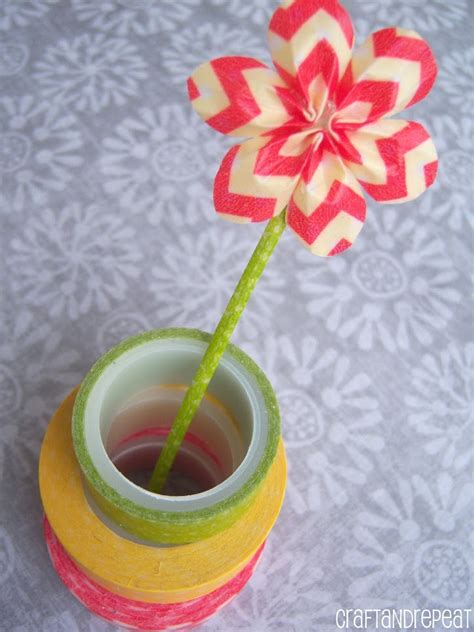 a red and white flower sticking out of a cup filled with liquid on top of a table