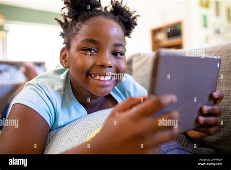 Portrait Of Smiling African American Girl With Digital Tablet Lying On