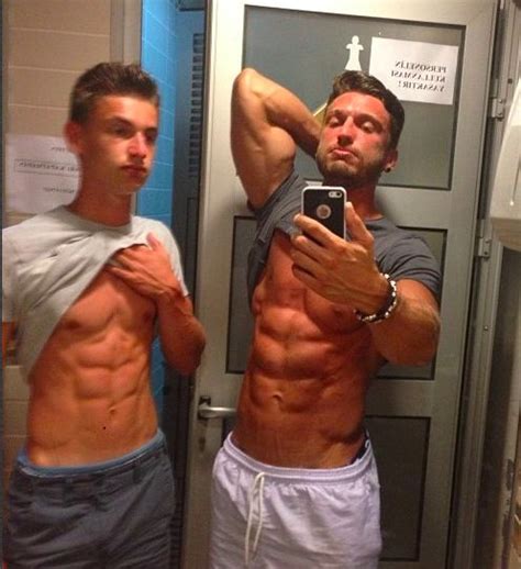 two very sexy guys pose together in a mirror for a post gym selfie showing their stunning bodies