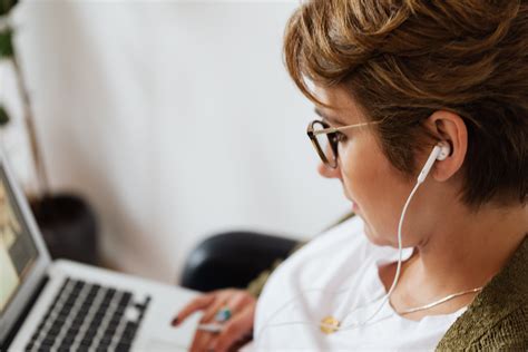 Focused Woman Using Laptop And Listening To Music In Earphones · Free