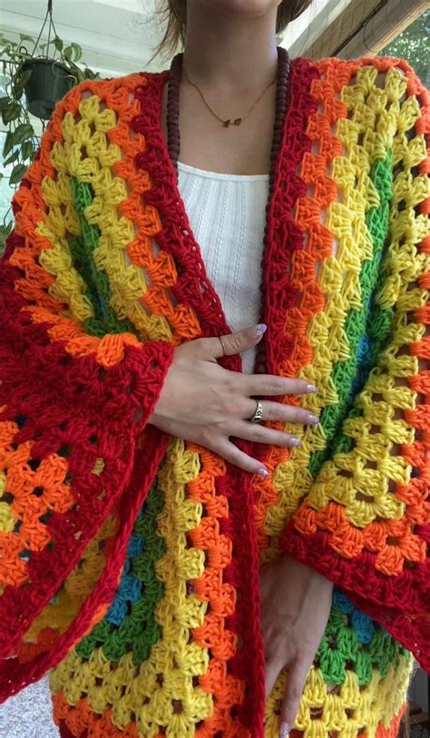 A Woman Wearing A Multicolored Crocheted Shawl With Her Hands On Her Hips