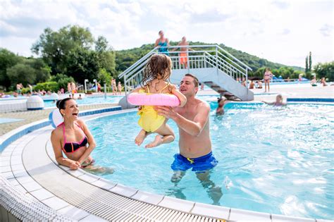young mother  father lifting   daughter  inflatable ring  swimming pool  aqua