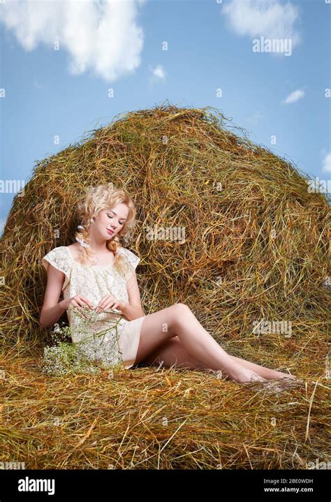 Portrait Of Beautiful Blonde Country Girl Sittitng On Yellow Hay With