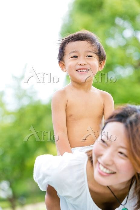 公園で裸の息子を背負う母親 の写真素材 アフロ