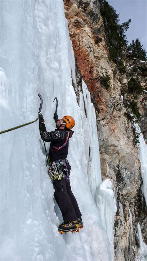 Male Ice Climber On A Steep Frozen Waterfall On A Beautiful Winter Day