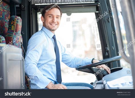 Handsome Bus Driver Is Sitting At Steering Wheel He Is Looking At The
