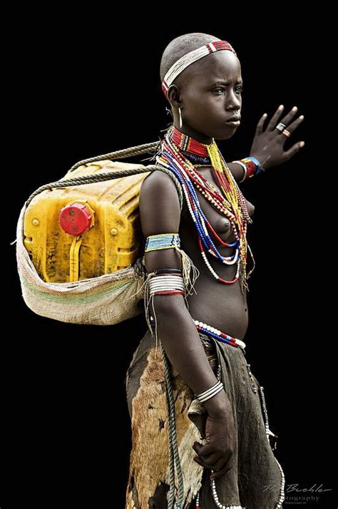 An African Woman Carrying A Yellow Bag On Her Back And Wearing Jewelry Around Her Neck