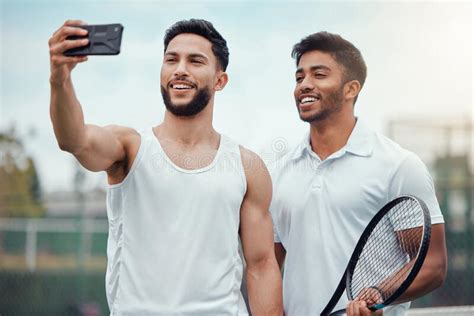 Portrait Of Two Smiling Ethnic Tennis Players Taking Selfie On
