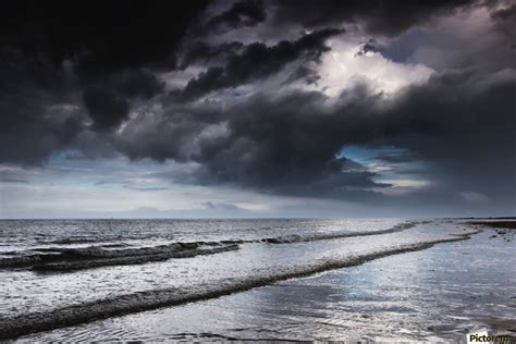 Dark Storm Clouds Over The Ocean With Waves Rolling Into