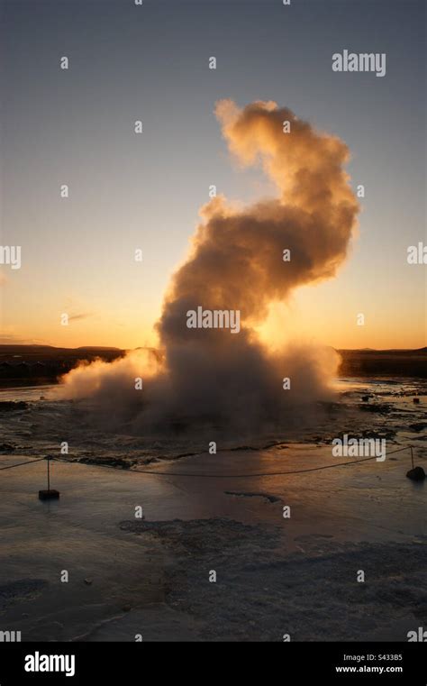 Steam Rises From A Geyser Eruption In Front Of The Setting Sun In
