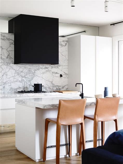 Whatever you need, the range has a chair for you. | KITCHEN | #white kitchen + black range hood + marble counter + backsplash + leather wrapped ...
