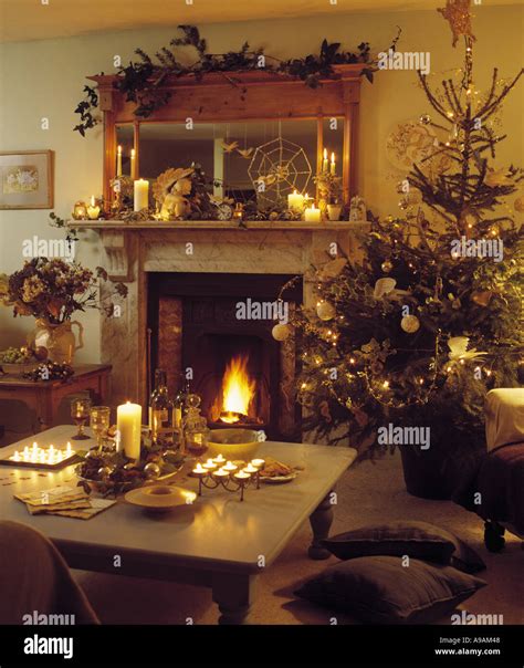 Christmas Tree Beside Fireplace With Lighted Fire In Warm Living Room