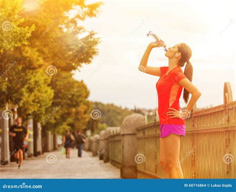 Young Woman Drinking Water After Running In The City Stock Photo
