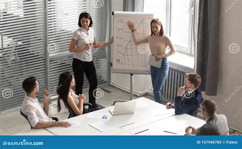 Professional Female Business Trainers Giving Flip Chart Presentation To