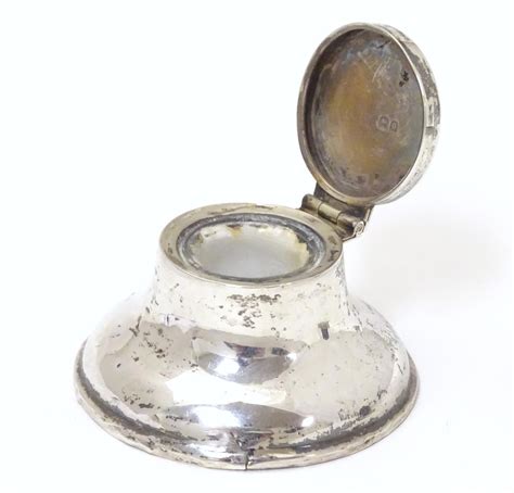 A Small Silver Capstan Shaped Inkwell With Hinged Lid And Glass Liner