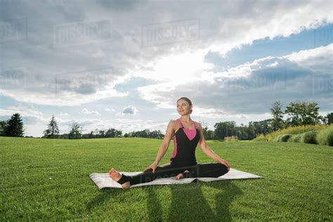Smiling Woman Performing Half Upright Seated Angle Yoga Pose On Green