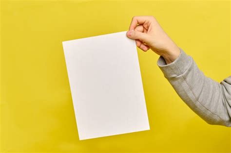 Premium Photo Man Hands Holds A White Paper Sheet On A Yellow Background
