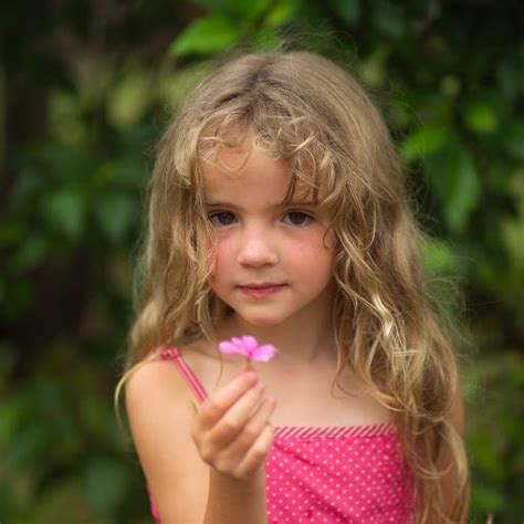 Very Young Girl Faces Young Girl Holding Pink Flower At