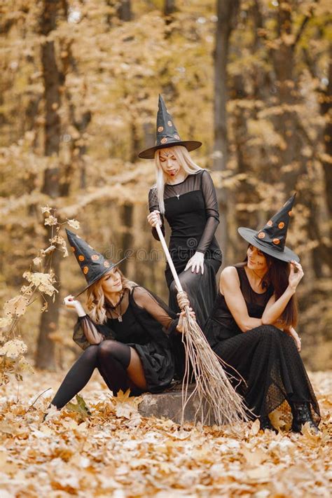 Three Black Witches In Forest On Halloween Holding A Broom Stock Photo