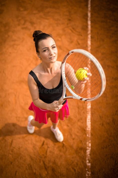 Top View Of Attractive Young Woman Tennis Player Serving On A Clay