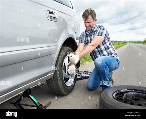 Man With Jack Changing A Spare Tire Of Car On Road Stock Photo Alamy