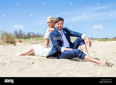 Braut Und Bräutigam Sitzen Rücken An Rücken Am Strand Stockfotografie Alamy