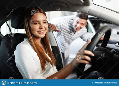 Young Attractive Woman Looking For A New Car In A Showroom Stock Photo