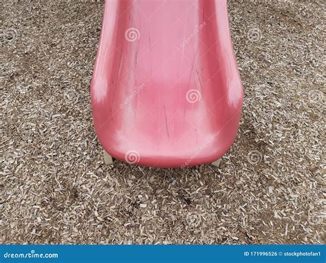 Red Plastic Slide With Scratches Or Marks And Wood Chips Or Mulch Stock