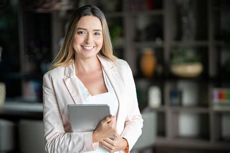 Latin American Real Estate Agent Holding A Tablet And Looking At Camera