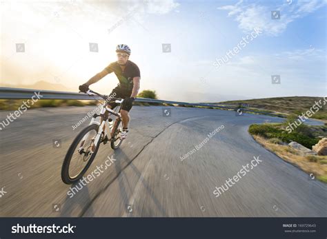 Cyclist Man Riding Mountain Bike In Sunny Day On A Mountain Road Image With Flare Imagen De