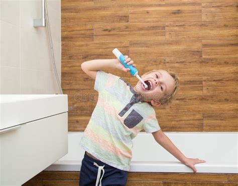 A Five Year Old Boy Is Brushing His Teeth In The Bathroom Stock Photo