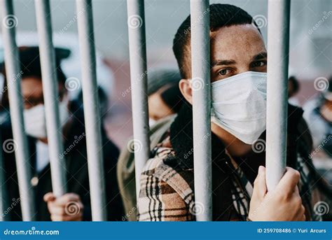We Need a Saviour. a Young Man Wearing a Mask while Stuck Behind a Gate