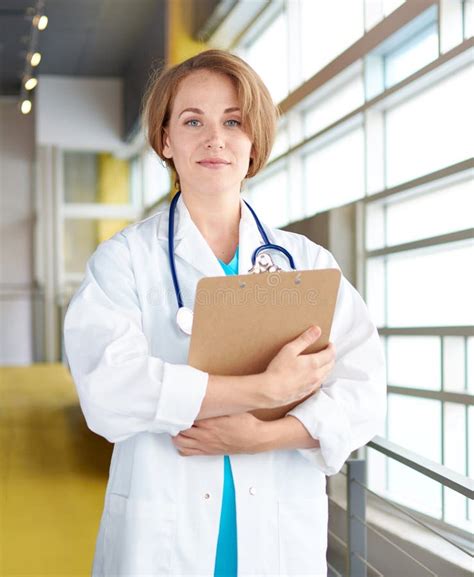Portrait Of A Female Doctor Holding Her Patient Chart In Bright Modern