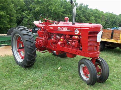 An Old Red Farmall Tractor Parked In The Grass