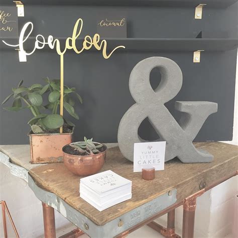 A Table With A Sign And Potted Plant On It That Reads London And Baker