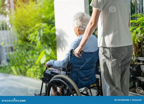 caregiver help and care asian senior or elderly old lady woman patient sitting on wheelchair to