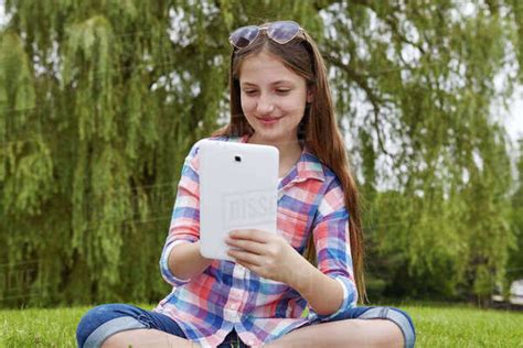 Preteen Girl Sitting In A Park Holding A Tablet Toronto Ontario Canada Stock Photo Dissolve