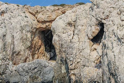 Large Cave Entrances In A Stone Cliff Above The Sea In Cyprus Stock