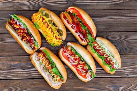 Lot Of Big Delicious Hot Dogs With Sauce And Vegetables On Wooden
