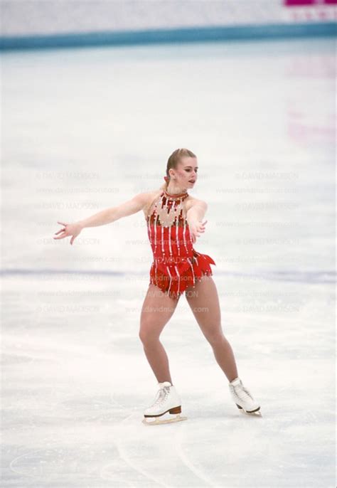 A Female Figure Skating On The Ice In A Red Dress And White Shoes With